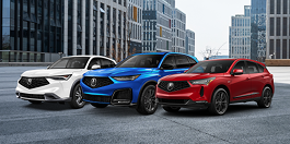 Vue de trois quarts avant d’un RDX rouge, d’un MDX bleu et d’un ADX blanc stationnés en rangée. De grands immeubles se trouvent en arrière-plan. 