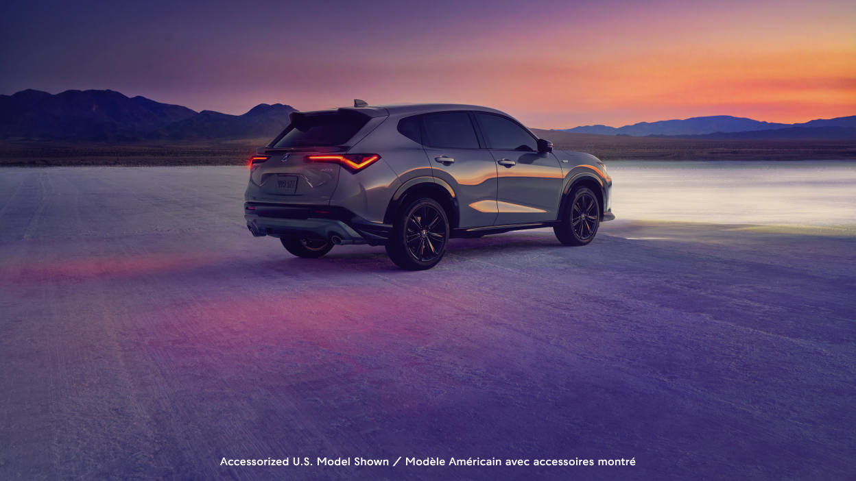 Wide rear-view shot of an Acura ADX with a dusky sunset in the background. 