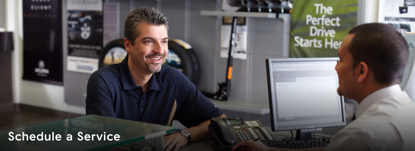 View of man sitting at a desk,  interacting with an Acura specialist.