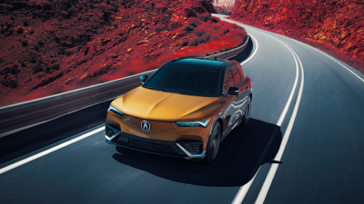 Vue de 3/4 à vol d'oiseau d’un ZDX or roulant sur une autoroute de montagne. Une partie de l’image est saturée de couleur, de sorte que la poussière sur les côtés de l’autoroute est rouge.